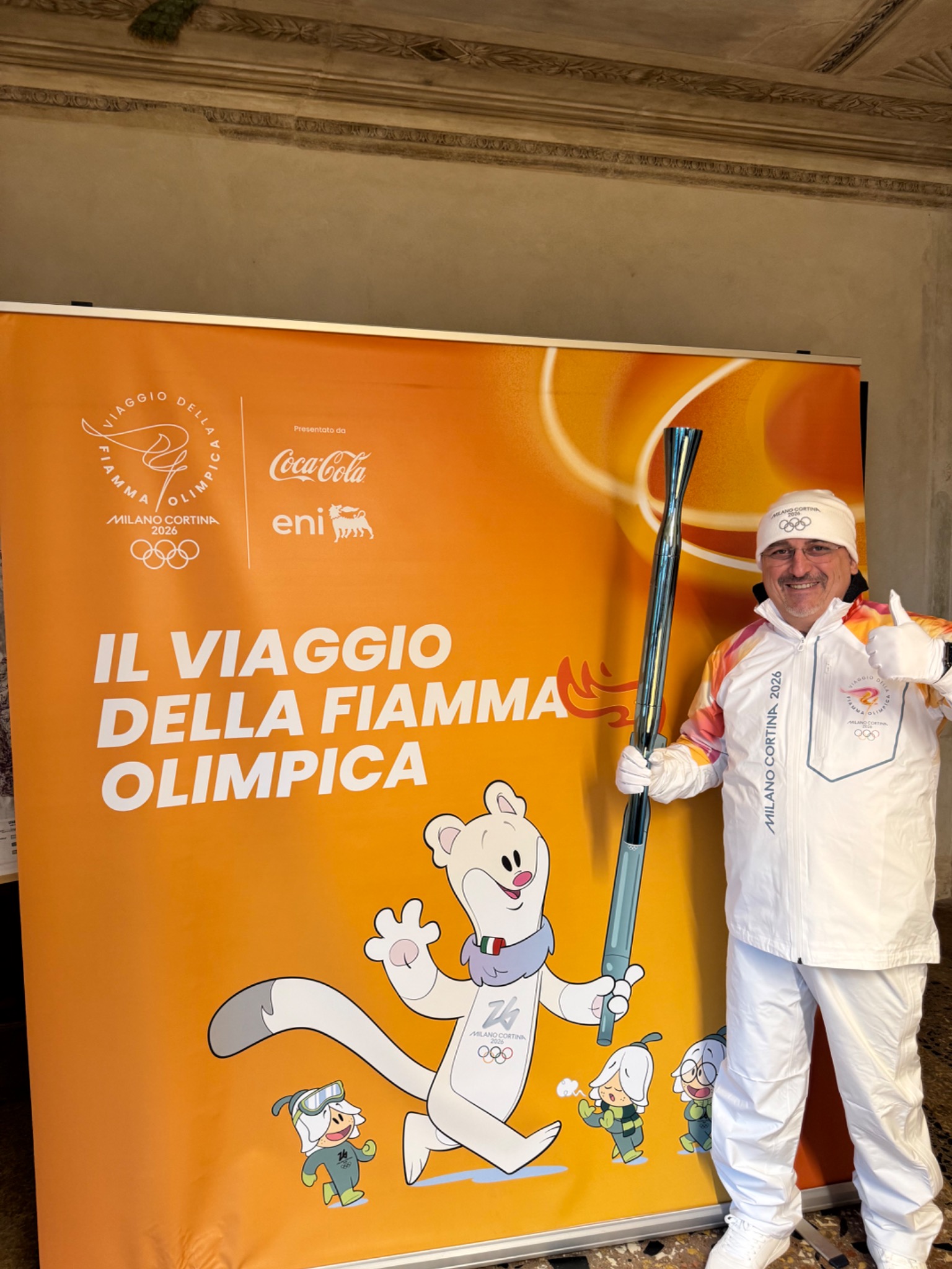 Max Conti in divisa ufficiale da tedoforo con la torcia di Milano Cortina 2026